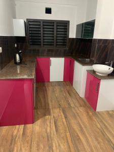 una cocina con armarios de color rosa y blanco y fregadero en Wayanad Rooms Izza en Sultans Battery