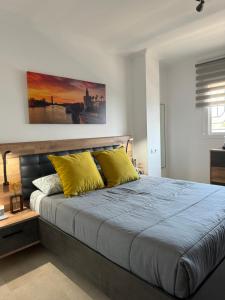 een slaapkamer met een groot bed met gele kussens bij Apartamento en Arahal Sevilla in El Arahal