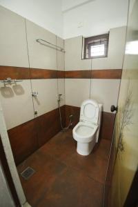 a bathroom with a toilet and a glass shower stall at Wayanad Rooms Izza in Sultan Bathery
