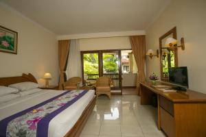 um quarto com uma cama, uma secretária e uma televisão em Parigata Resorts and Spa em Sanur