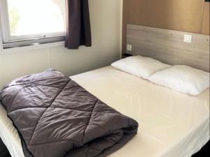 a bed with two pillows on it in a room at Camping Beau Rivage in Mèze