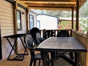 een tafel en stoelen op een veranda met een tafel bij Camping Beau Rivage in Mèze