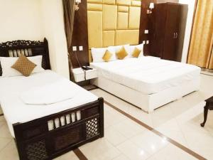 a bedroom with two beds and a table and chairs at Hotel PAK Continental Multan in Multan