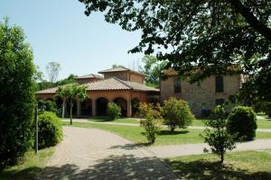 une grande maison en briques avec un chemin en face de celle-ci dans l'établissement Agriturismo La Fattoria, à Panicarola