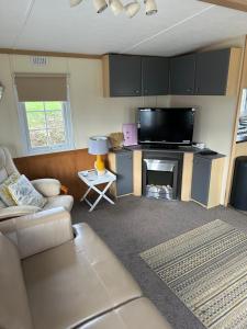 a living room with a couch and a flat screen tv at Static Mobile home set in our 20 acres of farmland in Horspath