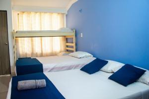 two beds in a room with blue walls at Casa hotel las gaviotas II in Santa Marta