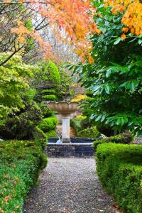a fountain in the middle of a garden with trees at Gardener's Cottage in Lancaster