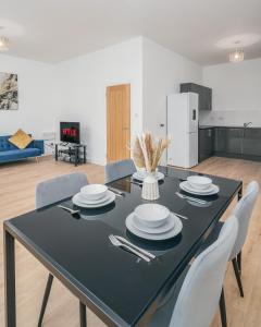 uma mesa de jantar preta com pratos brancos e talheres em Contractors I Working professionals I Relocators - Near Train Station and Airport em Luton