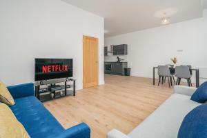 ein Wohnzimmer mit einem blauen Sofa und einem TV in der Unterkunft Contractors I Working professionals I Relocators - Near Train Station and Airport in Luton
