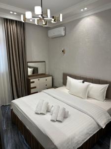 um quarto com uma grande cama branca e 2 almofadas em YakkaSaray Premium Apartment em Tashkent