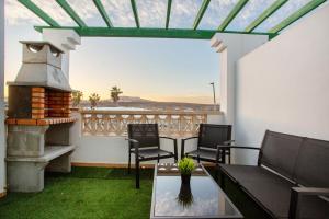 een balkon met een tafel en stoelen en een open haard bij Casa David Prieto 2 Habitaciones in Caleta De Fuste