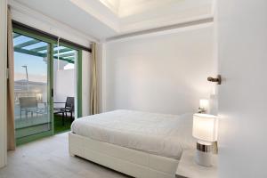 a white bedroom with a bed and a balcony at Casa David Prieto 2 Habitaciones in Caleta De Fuste +16 photos
