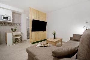 een woonkamer met een bank en een tv aan de muur bij Casa David Prieto 2 Habitaciones in Caleta De Fuste