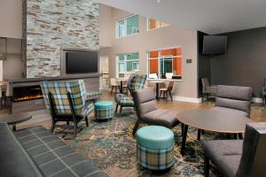 una sala de estar con chimenea, sillas y mesas. en Residence Inn by Marriott Indianapolis Plainfield en Plainfield