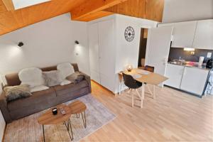 ein Wohnzimmer mit einem Sofa und einem Tisch sowie eine Küche in der Unterkunft Charmant studio avec parking gratuit in Ovronnaz