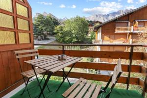 een houten tafel en een bank op een balkon bij Charmant studio avec parking gratuit in Ovronnaz