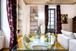 uma sala de estar com uma mesa de vidro e cadeiras em Dimora Novecento [PORTA NUOVA-CENTRO] em Turim