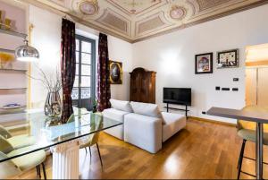 uma sala de estar com um sofá branco e uma mesa de vidro em Dimora Novecento [PORTA NUOVA-CENTRO] em Turim