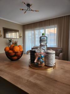 una mesa con una botella de alcohol y un tazón de naranjas en Apartament ASB Oradea, en Oradea