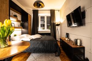 Schlafzimmer mit einem Bett, einem Tisch und einem TV in der Unterkunft Old Town Heart XII - Poznańska Luxury Loft in Warschau