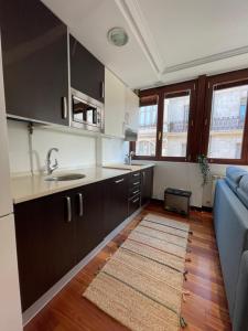 een keuken met zwarte kasten en een blauwe bank bij Atuaire Home Luz de Burgos II Centro con Parking Incluido in Burgos