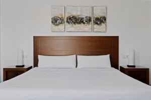 a bedroom with a white bed and three paintings on the wall at Prinsotel Villas Cala Galdana in Cala Galdana +29 photos