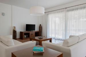 sala de estar con muebles blancos y TV en Prinsotel Villas Cala Galdana en Cala Galdana