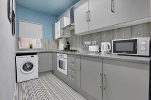 uma cozinha com armários brancos e uma máquina de lavar e secar roupa em Stylish 3 Bed Apartment, Abbeydale Rd - Sleeps 8, FREE Parking & Netflix em Sheffield