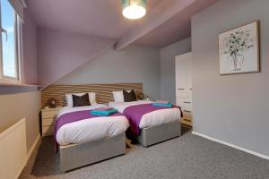 two beds in a small room with purple walls at Stylish 3 Bed Apartment, Abbeydale Rd - Sleeps 8, FREE Parking & Netflix in Sheffield