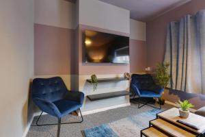 uma sala de estar com duas cadeiras azuis e uma televisão em Stylish 3 Bed Apartment, Abbeydale Rd - Sleeps 8, FREE Parking & Netflix em Sheffield
