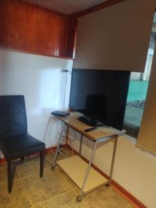 康康的住宿－Linda cabaña interior con piscina y entrada independiente en concon，一张桌子,电视机和椅子放在房间里