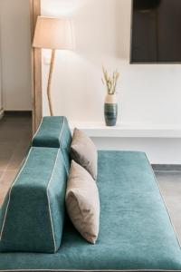 a green couch with two pillows and a lamp at Villa Nefeli - Ionian Treasure Villas in Argostoli