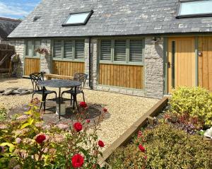 un patio con mesa y sillas frente a una casa en Church Farm Barn Annex, en Somerton