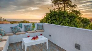 eine Terrasse mit einem Sofa und einem Tisch mit Weingläsern in der Unterkunft Arktos Sunset Villa in Kefalonia