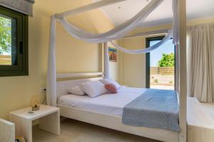 um quarto com uma cama de dossel branca e uma janela em Arktos Sunset Villa em Cefalônia