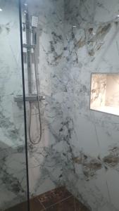 a shower in a bathroom with a marble wall at Private Room with attached Bathroom in The Hyde