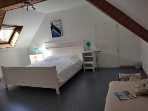 een slaapkamer met een groot wit bed op een zolder bij Petite Maison cosy avec jardin, bbq, campagne in Limerzel