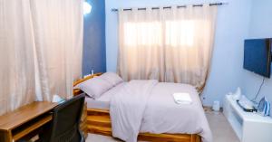 1 dormitorio con 1 cama con escritorio y monitor en Studio cosy en Lomé