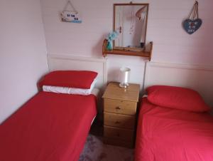 two beds in a room with red sheets and a mirror at Sea views in Bideford