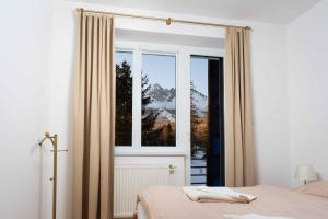 una camera da letto con finestra affacciata sulle montagne di Apartments Tatra Olla - Tatranská Lomnica a Tatranská Lomnica