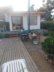 Casa con terraza de madera con banco y mesa en Linda cabaña interior con piscina y entrada independiente en concon, en Concón