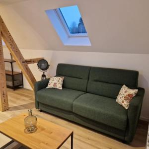 um sofá verde numa sala de estar com uma mesa em Résidence du Lac Blanc appartement chez Jérémy em Orbey