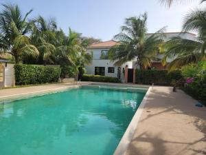 a swimming pool in front of a house with palm trees at Villa oasis n°5 in Gandigal