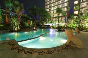 une grande piscine avec une statue à côté d'un bâtiment dans l'établissement Ijen Suites Resort & Convention, à Malang