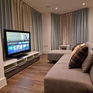 a living room with two couches and a flat screen tv at Charming & Large 1-Bedroom in the Heart of London in London
