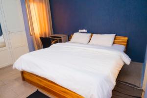 a bedroom with a large bed with white sheets at Studio cosy et confortable in Lomé