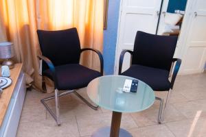 Duas cadeiras e uma mesa de vidro com controlo remoto em Studio cosy et confortable em Lomé