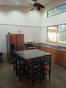 eine Küche mit einem Tisch, Stühlen und einem Kühlschrank in der Unterkunft Loma Linda Sarapiquí Casa Nueva NEW HOUSE 3bed/2bath in Tirimbina