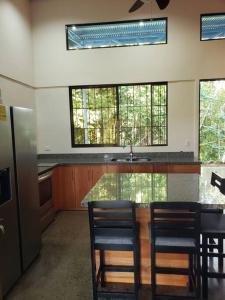 a kitchen with a counter with chairs and a sink at Loma Linda Sarapiquí Casa Nueva NEW HOUSE 3bed/2bath in Tirimbina