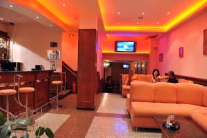 a lobby with two people sitting on couches and a bar at Семеен Хотел Сокол in Sandanski